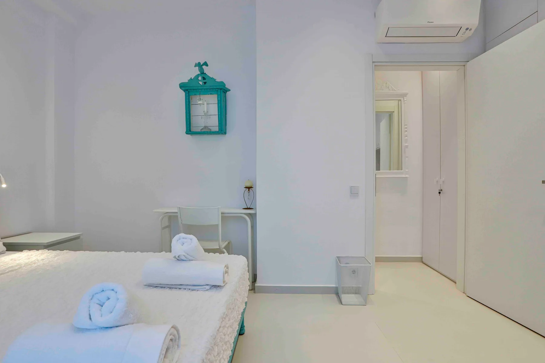 Un dormitorio luminoso con una cama y un pequeño escritorio junto a la pared.