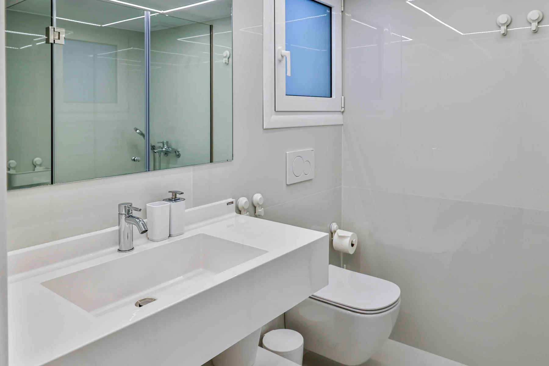 A bright bathroom with a wide sink and wall mirror.