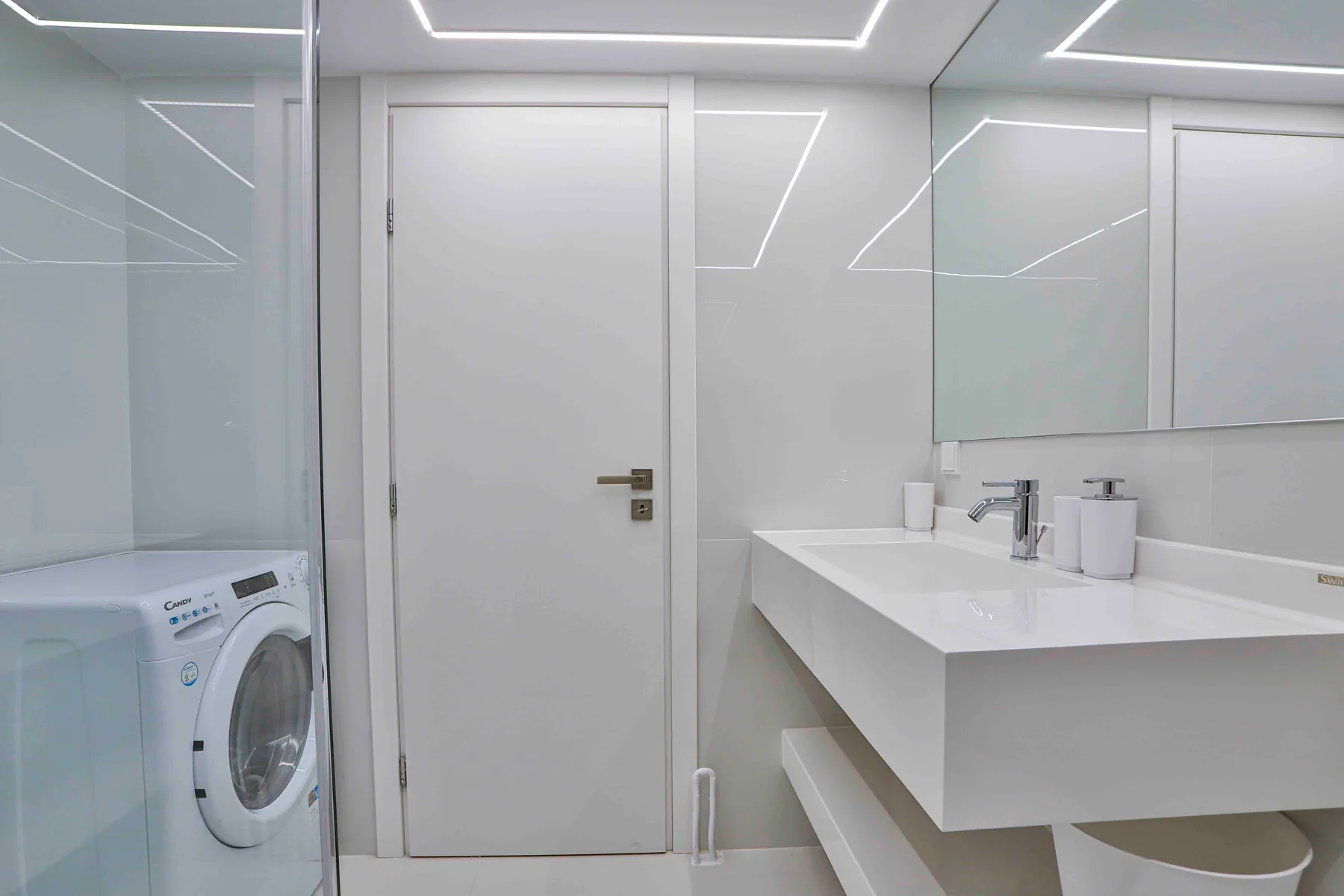 A modern bathroom with a washing machine and a white vanity.