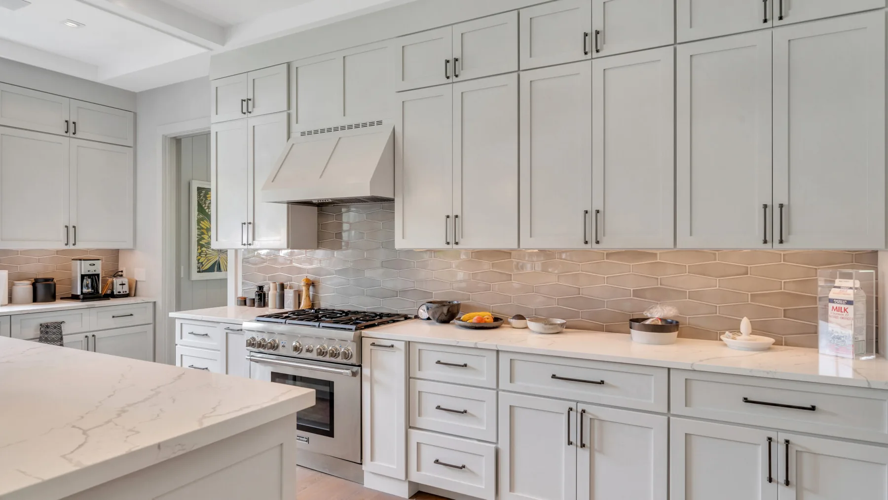 Una cocina luminosa con gabinetes blancos, una encimera larga y una isla central.