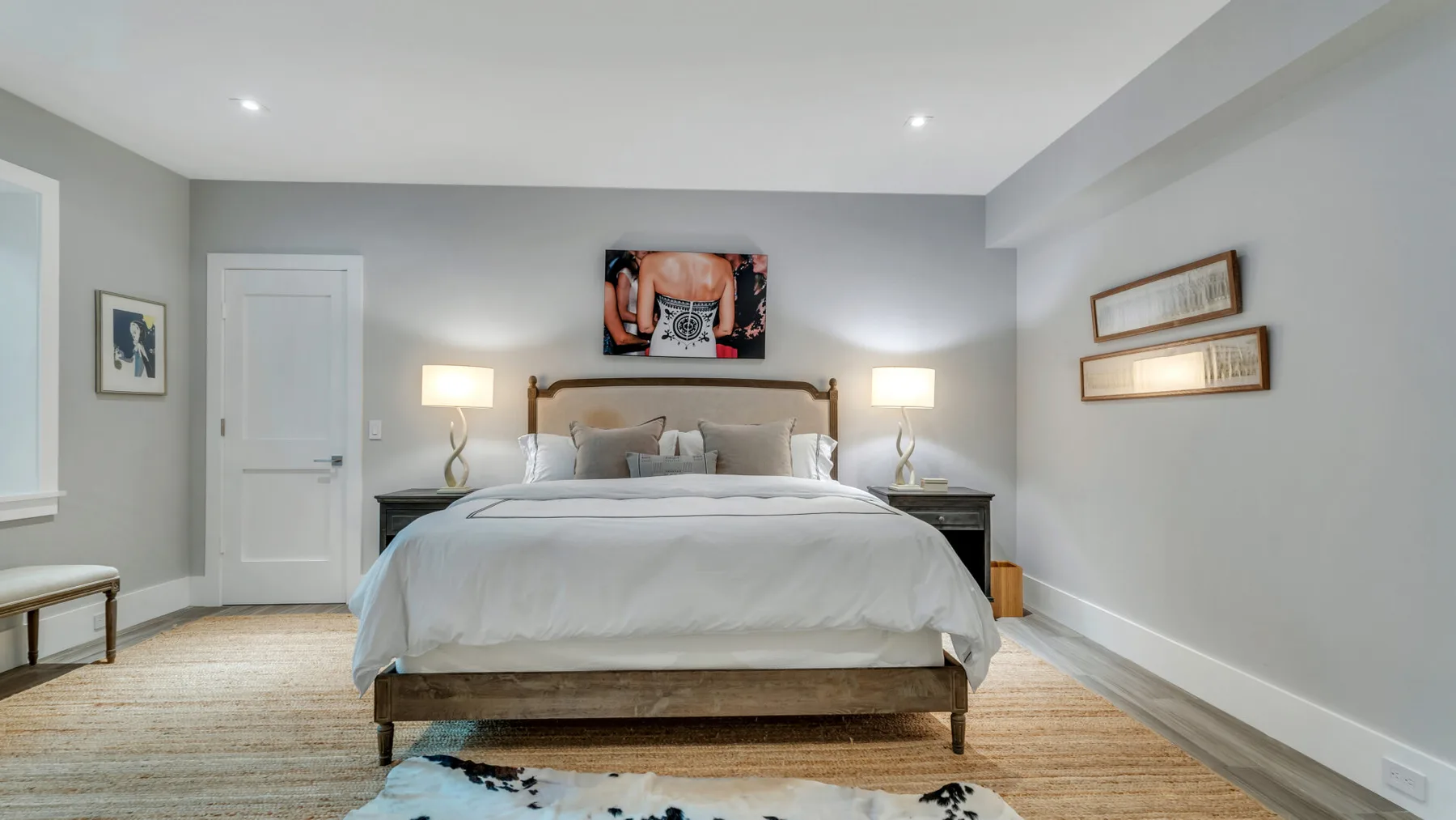 Un dormitorio con una cama bien tendida, mesas de noche y cuadros en la pared.