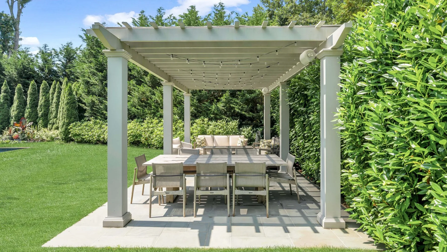 Un patio de jardín con pérgola cubre una mesa de comedor y asientos al aire libre.