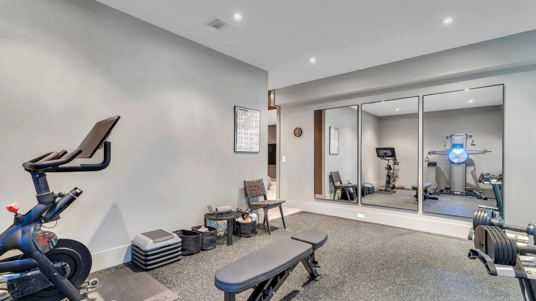 Un gimnasio en casa con equipo de ejercicio, pesas y un banco de entrenamiento.