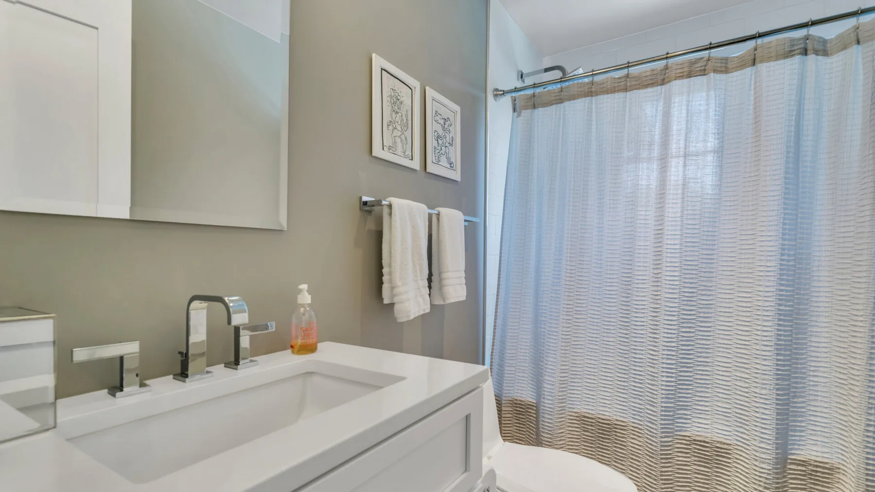 Un lavabo de baño con una amplia pila está junto a una ducha con cortina.
