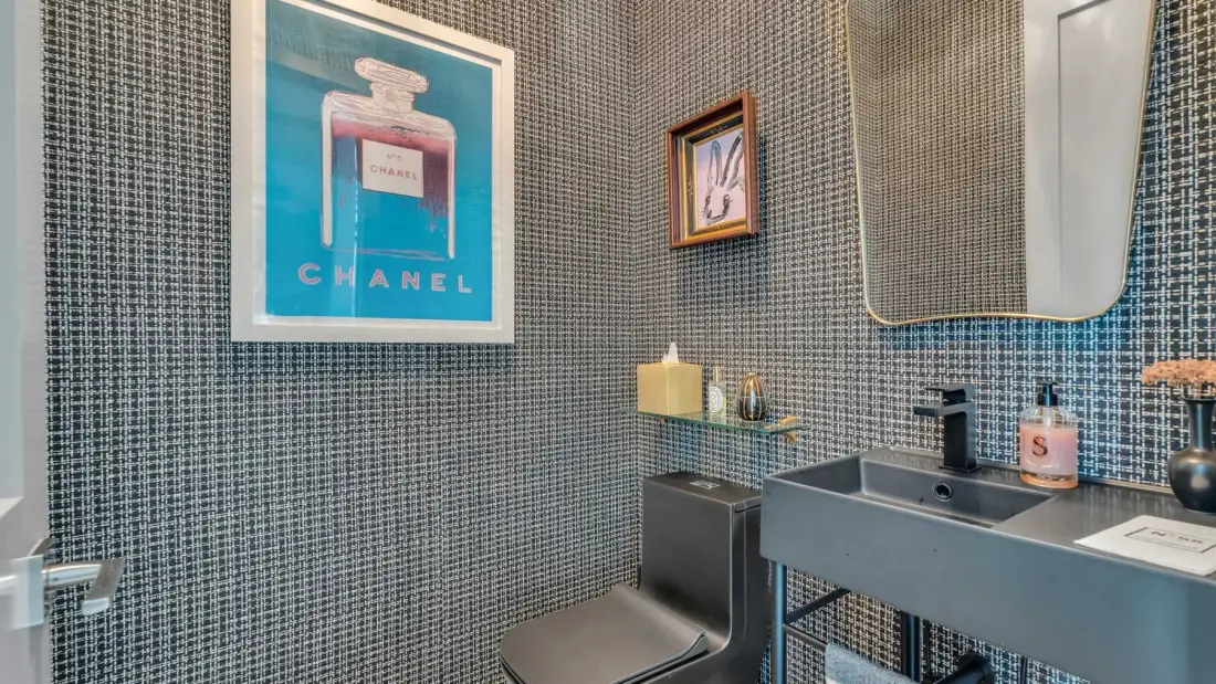 Un baño alicatado con un lavabo y cuadros en la pared.