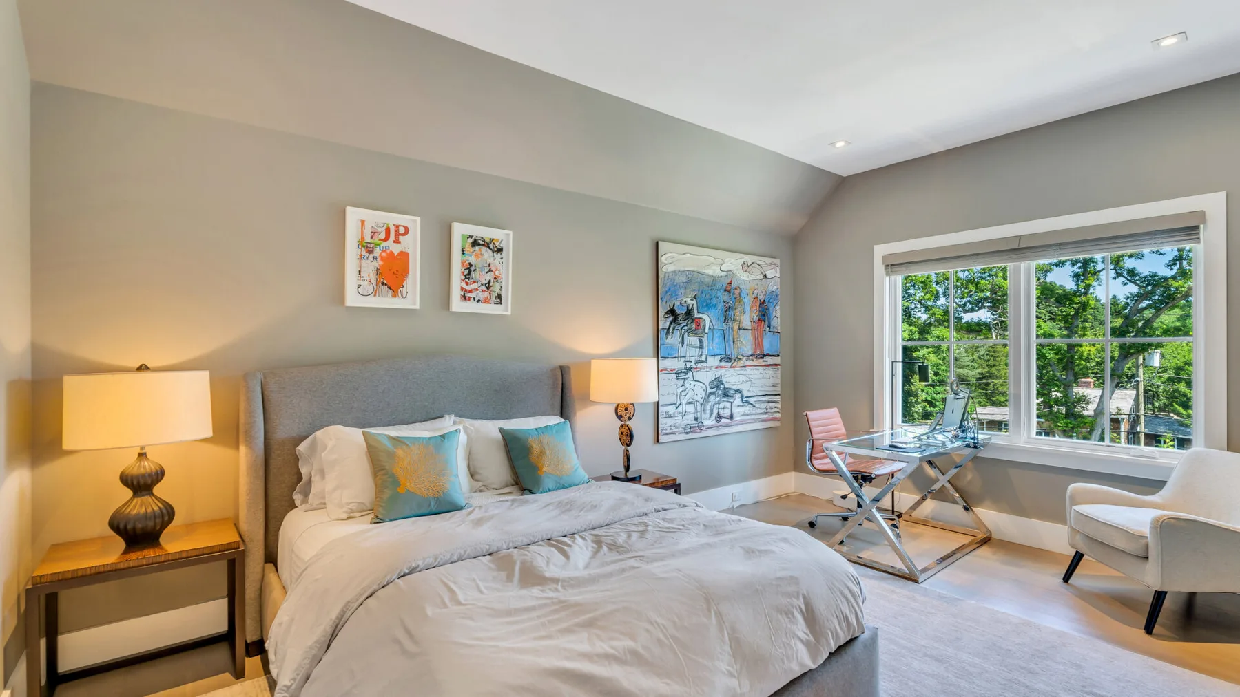 Un dormitorio con la cama tendida, cuadros en la pared y una ventana grande con vista a la vegetación.