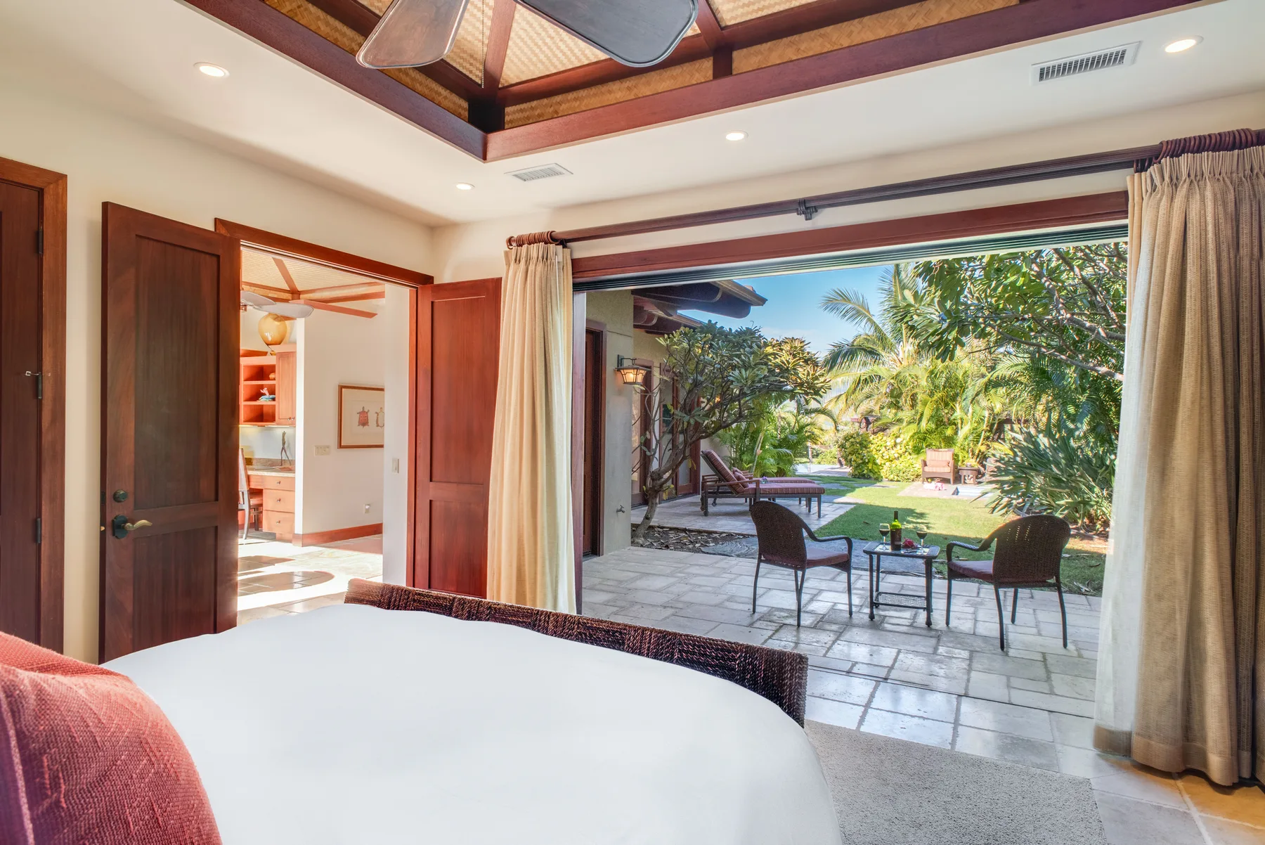 A bedroom opens onto a tiled patio and leafy garden.
