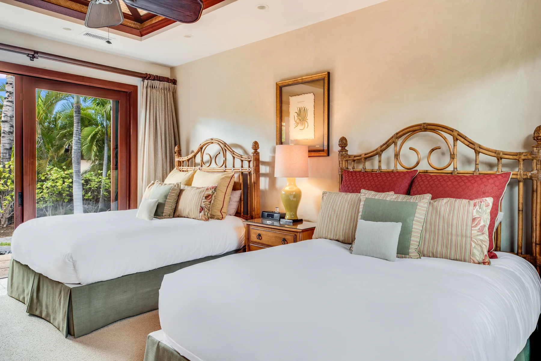 A bedroom with two beds, decorative wooden headboards, and a glass door overlooking greenery.