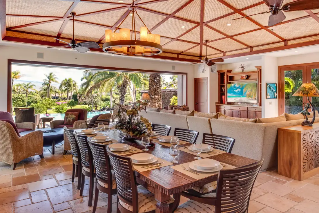 A dining area with a long table and seating beside an open living space.