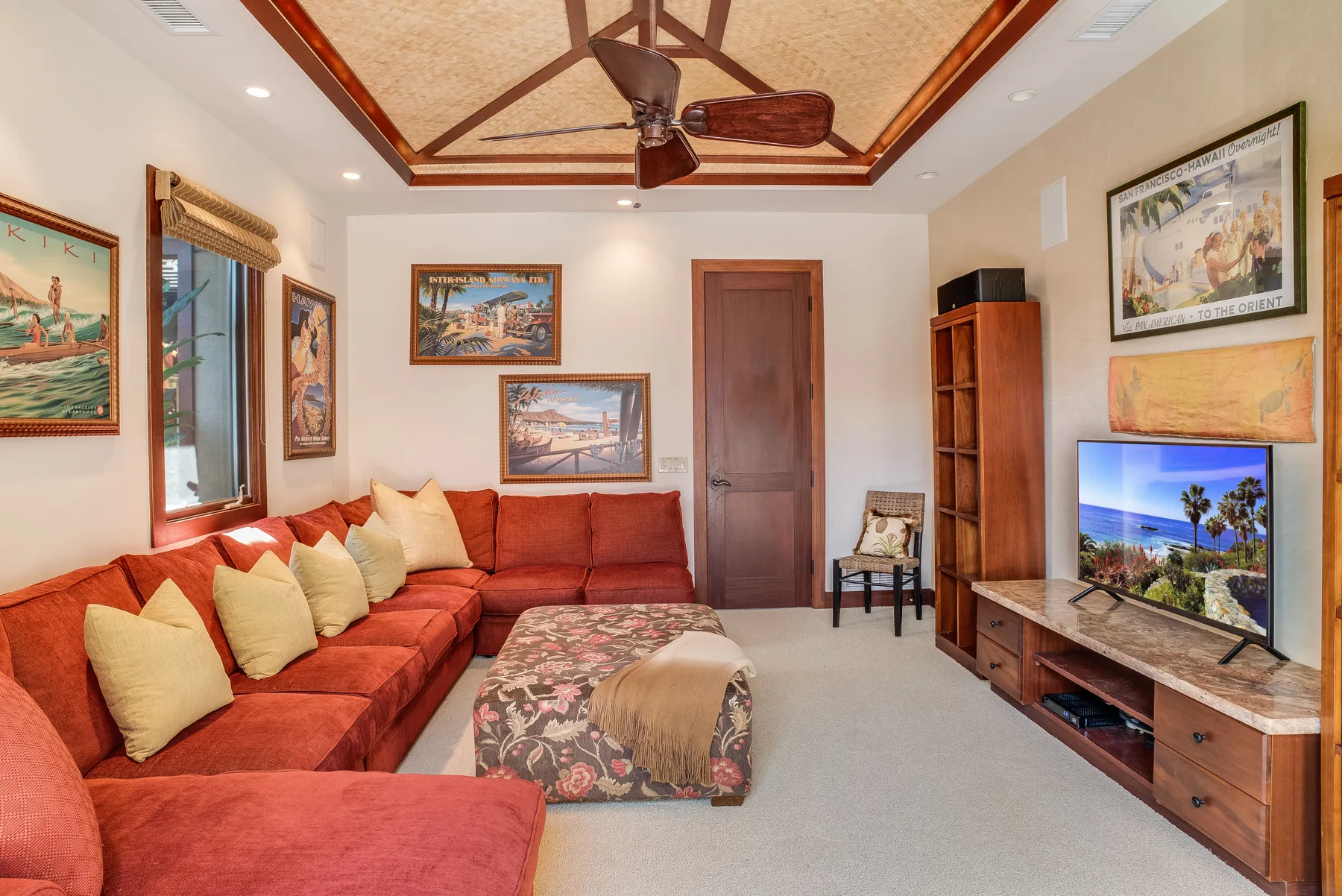 A living room with red seating, framed artwork, and a television.