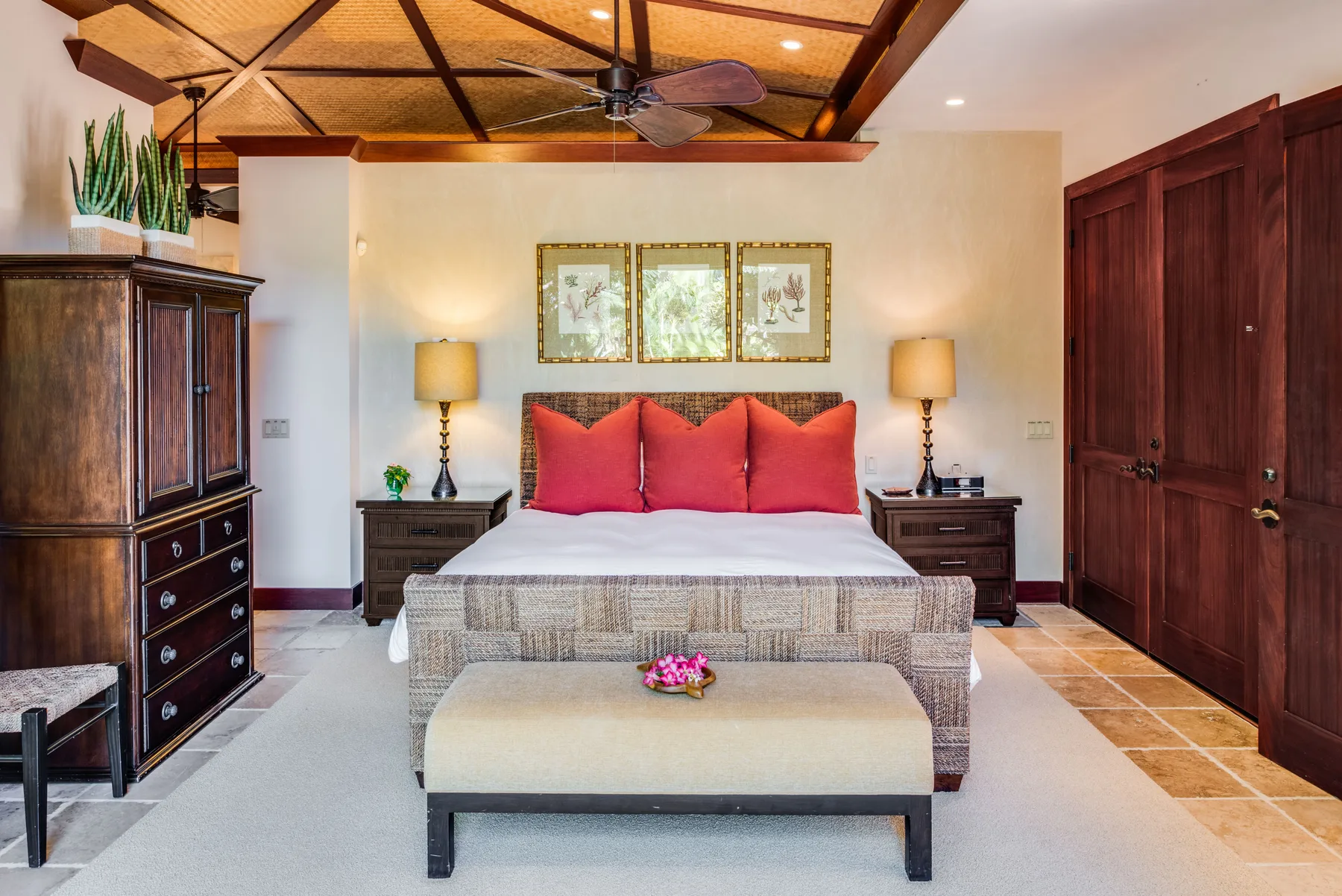 A bedroom with a bed, red pillows, and wooden ceiling beams.