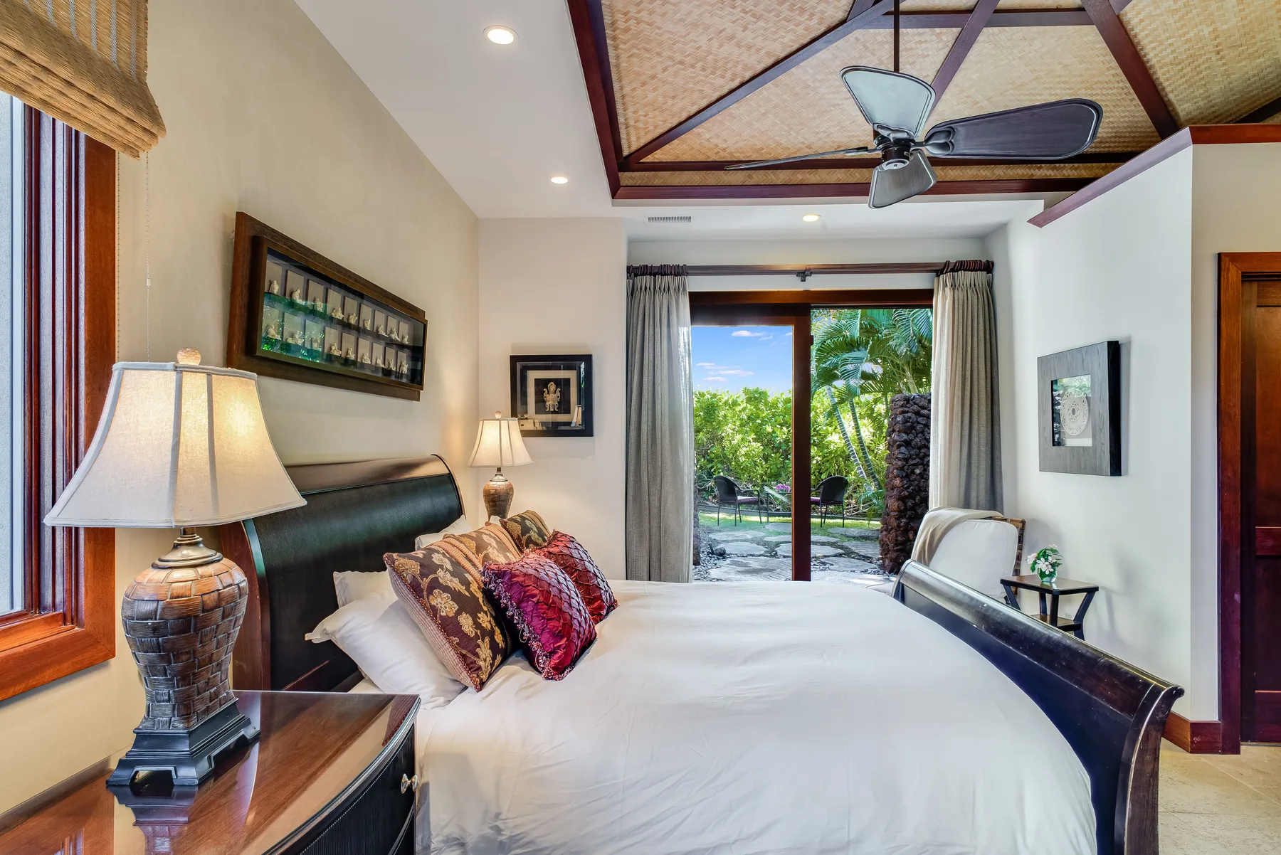 A bedroom with a large bed and sliding glass doors opening onto greenery.