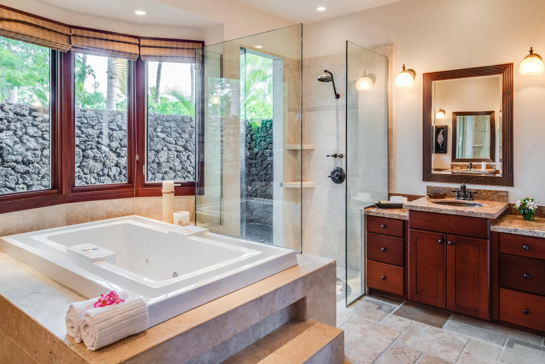 A bathroom with a large bathtub, glass shower, and wooden vanity.