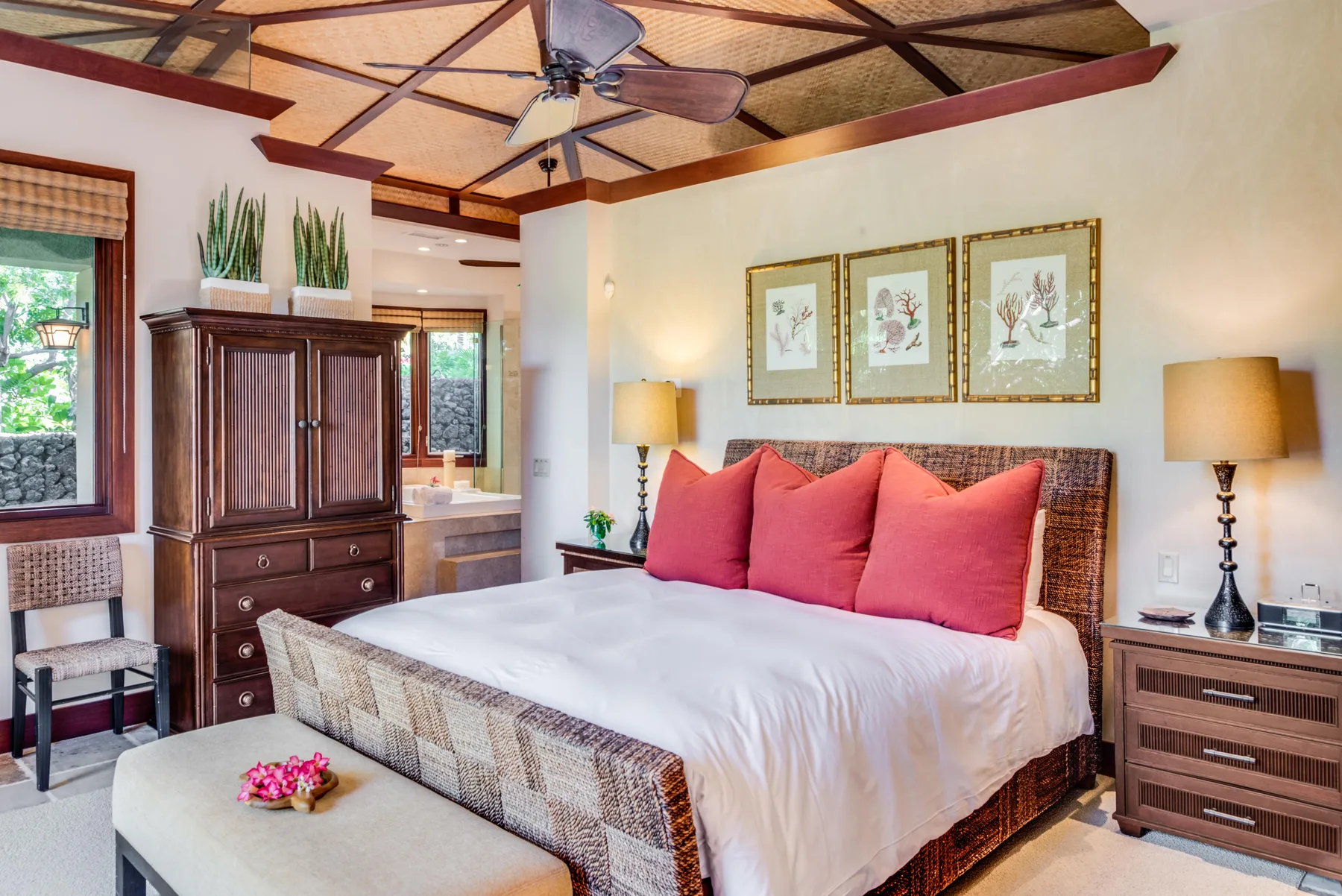 A bedroom with a large bed, red pillows, and framed artwork above the headboard.