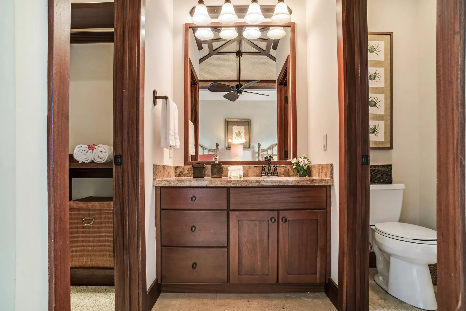 A bathroom vanity with a large mirror and a toilet beside it.
