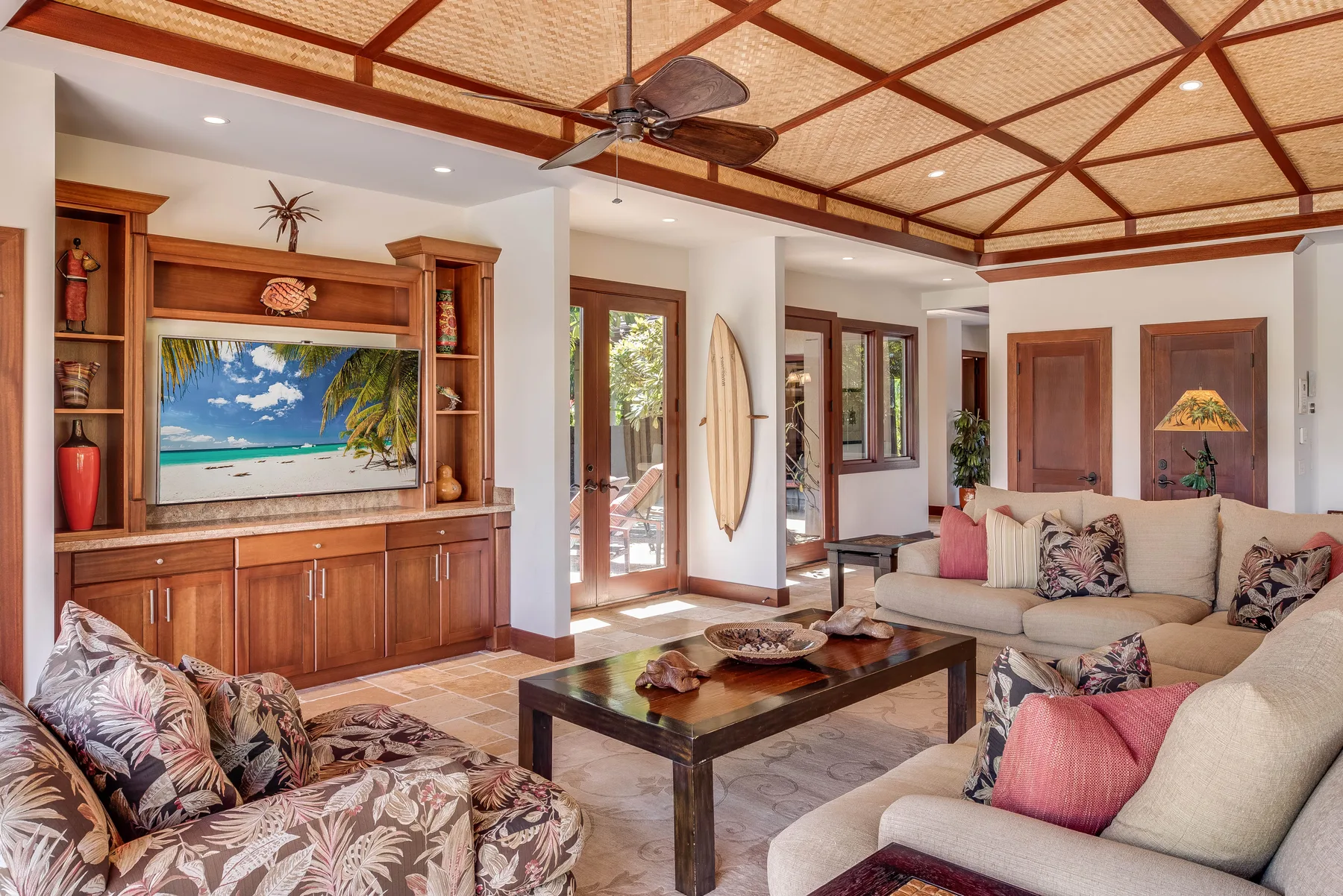 A bright living room with seating, a coffee table, and a wooden entertainment unit.