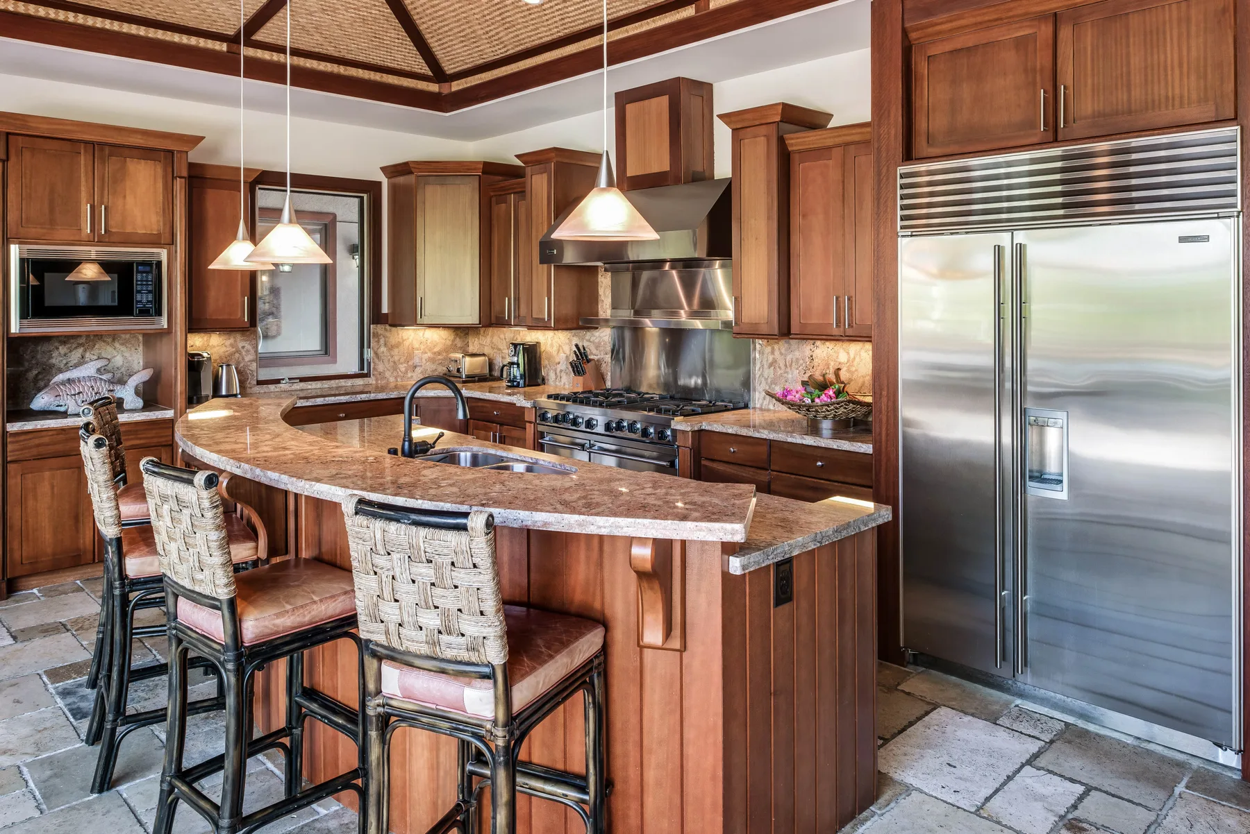 A spacious kitchen with a central island, bar seating, and stainless-steel appliances.