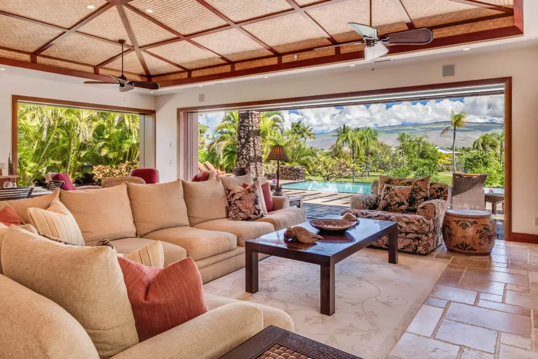 A spacious living room opens onto a tropical garden and pool.