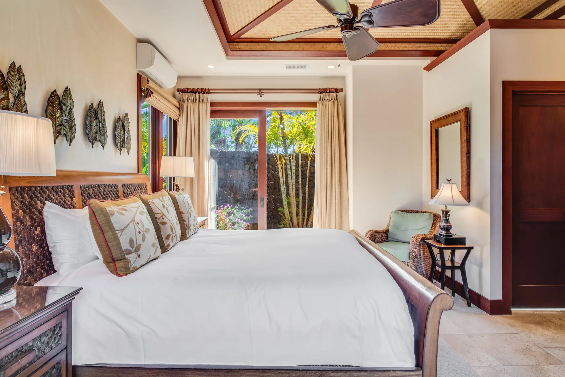 A bedroom with a large bed, bedside tables, and a window overlooking greenery.