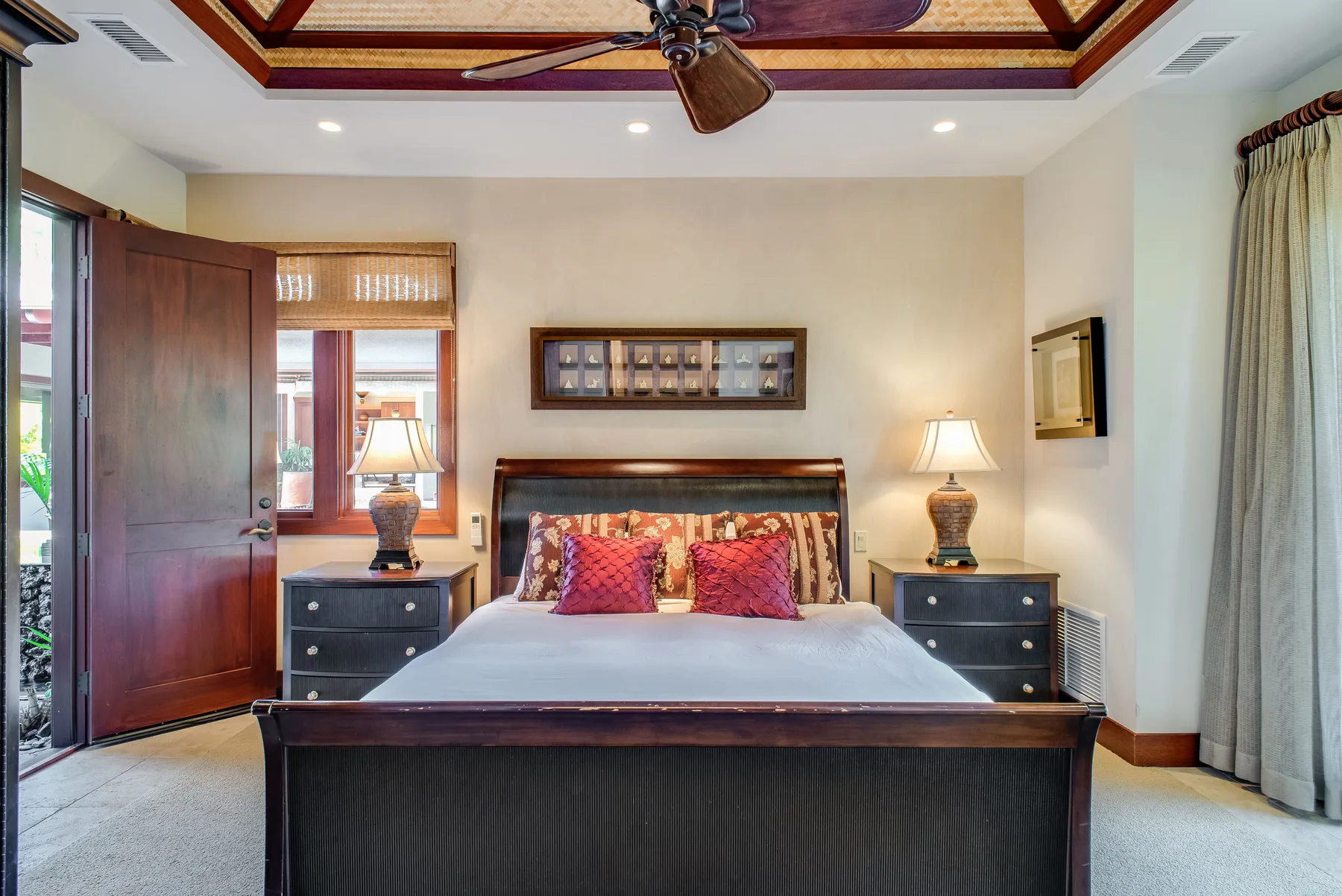 A bedroom with a bed, matching bedside tables, and a ceiling fan.