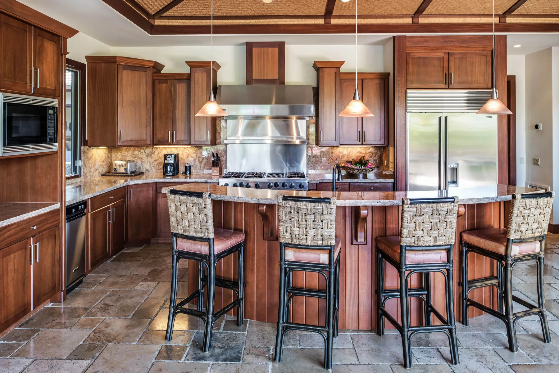 A kitchen with a large island, bar seating, and wooden cabinets.