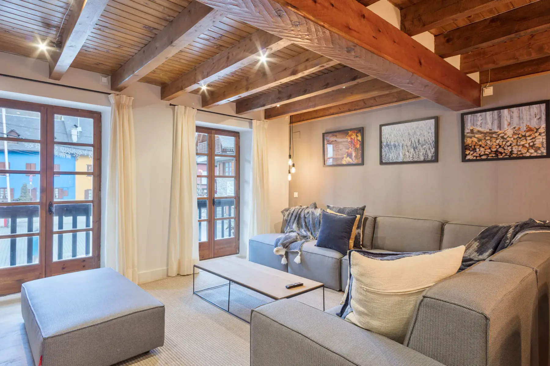A living room with a gray sectional sofa, a glass coffee table, and large windows.