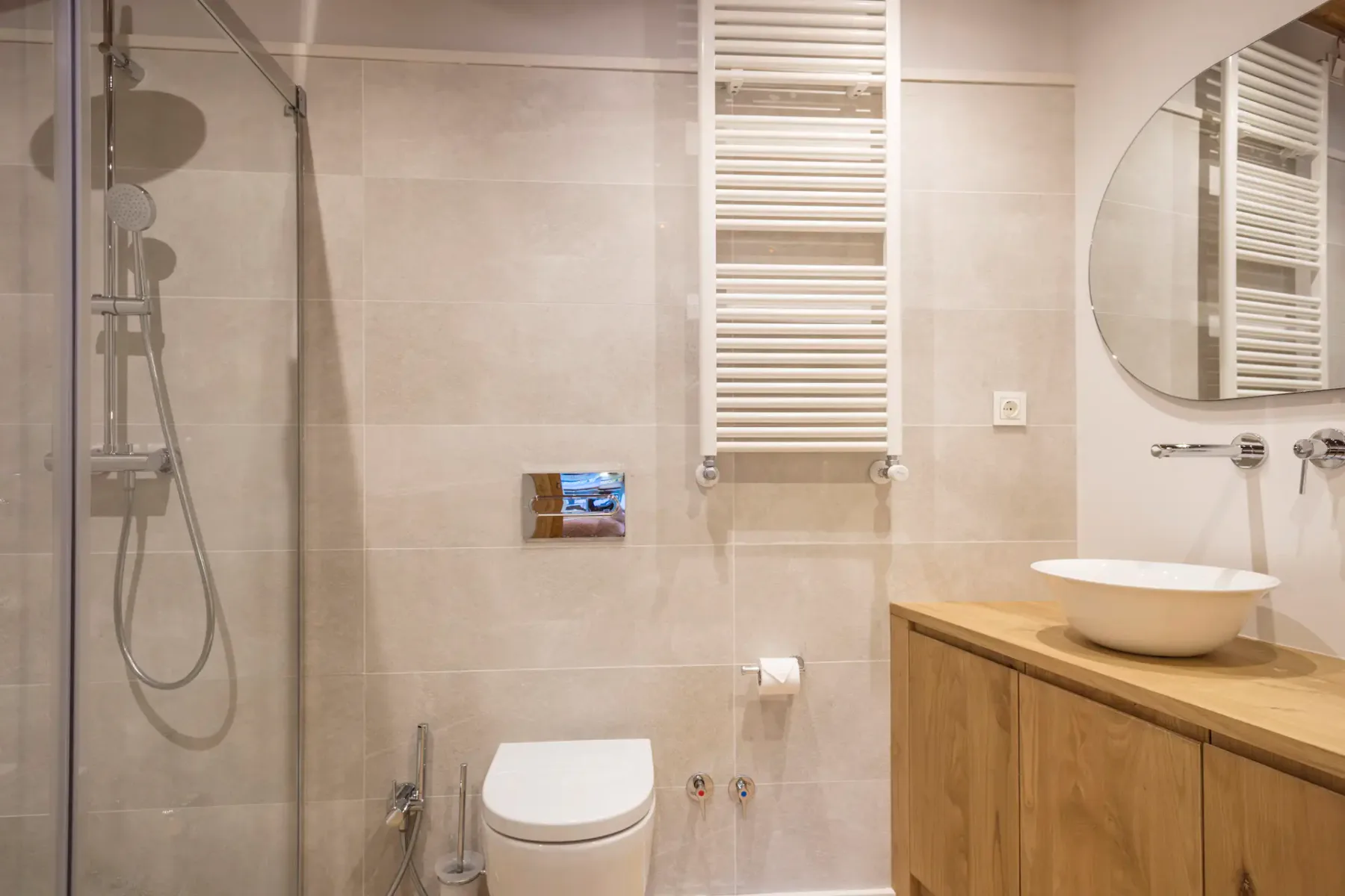 A bathroom with a shower, toilet, and wooden vanity.