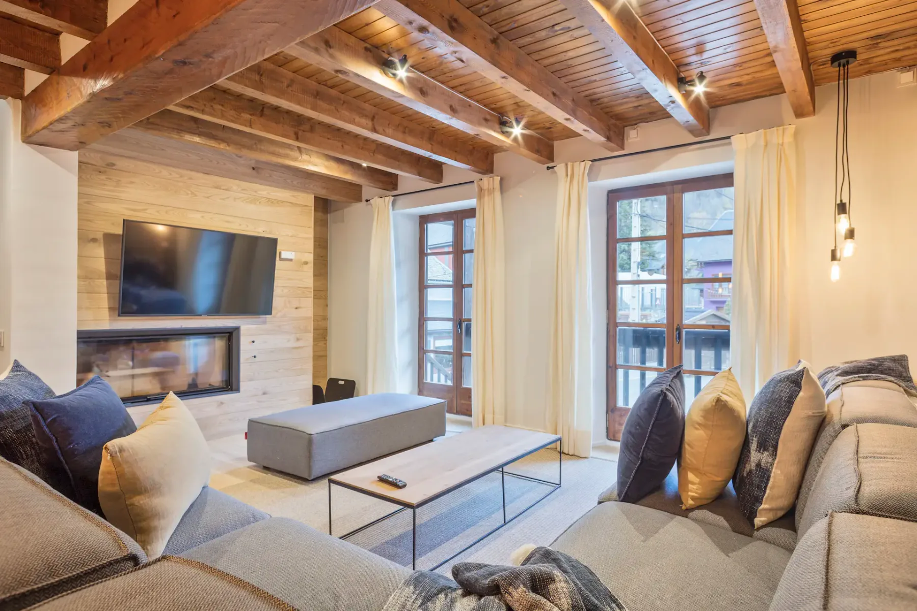 A living room with seating arranged around a coffee table and a wall-mounted television.