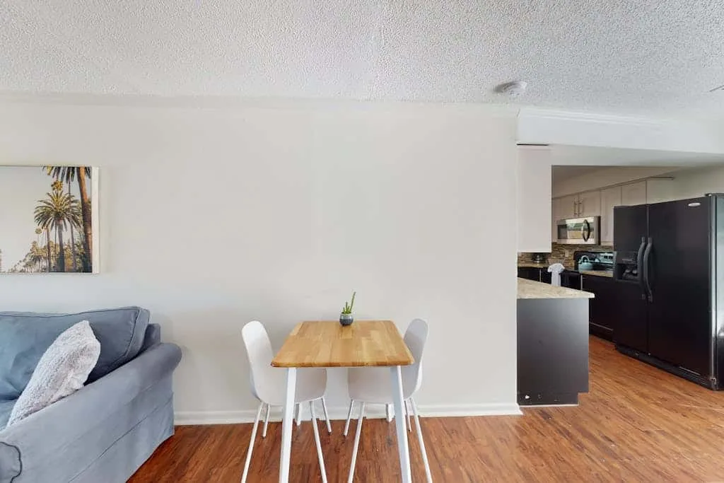A living and dining area with a wooden table and adjoining kitchen.