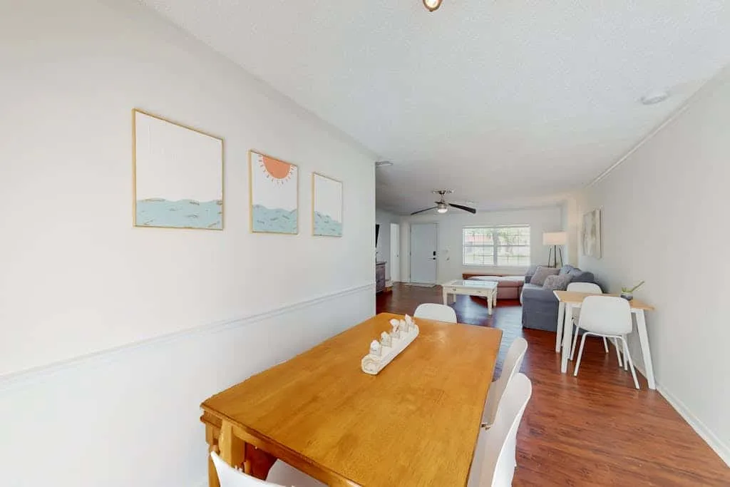A bright open living and dining area with a wooden table and seating.
