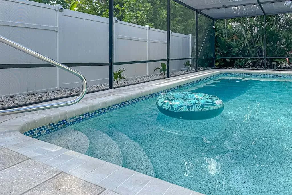 A swimming pool with a patterned inflatable ring floats beside the tiled edge.
