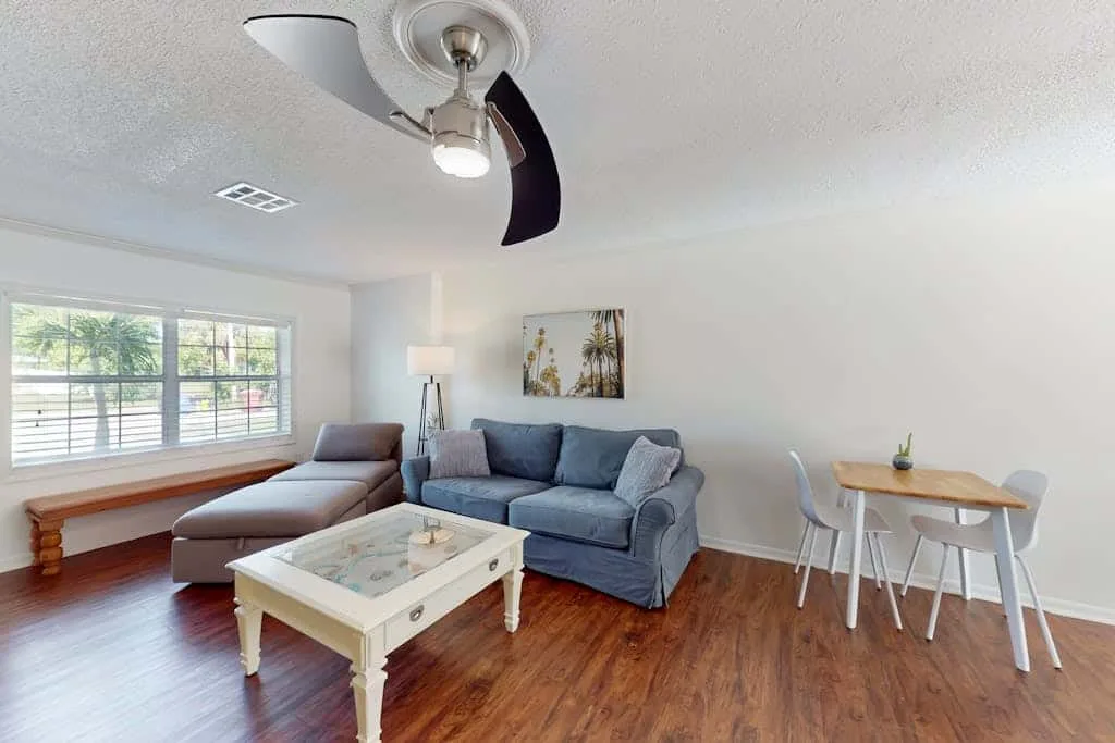 A living room with seating around a coffee table beside large windows.