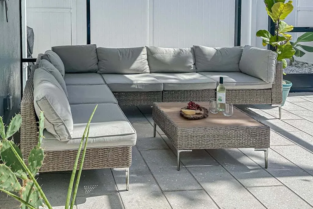 An outdoor patio seating area with a sectional sofa and low table.