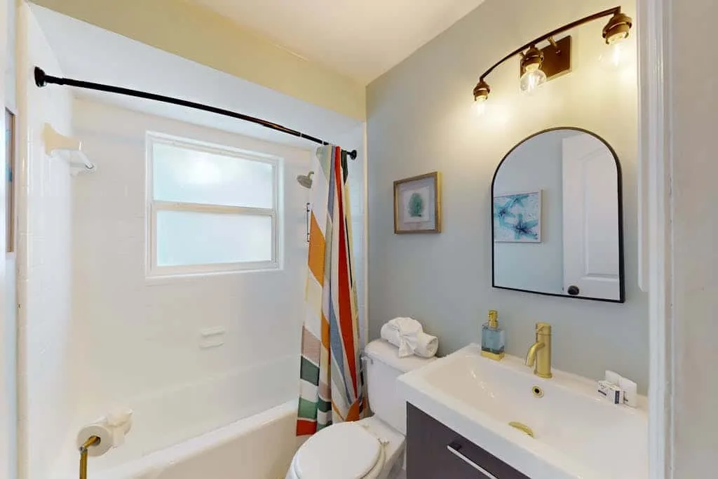 A bathroom with a bathtub, striped shower curtain, and sink.