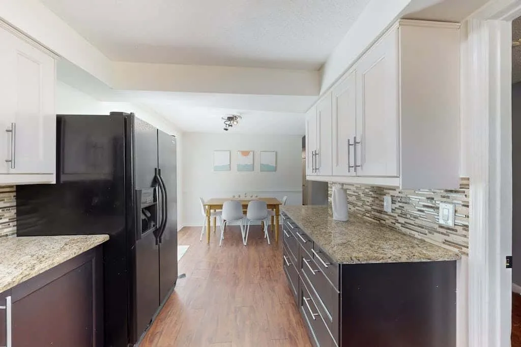 A bright kitchen with dark cabinets, stone counters, and a dining table.