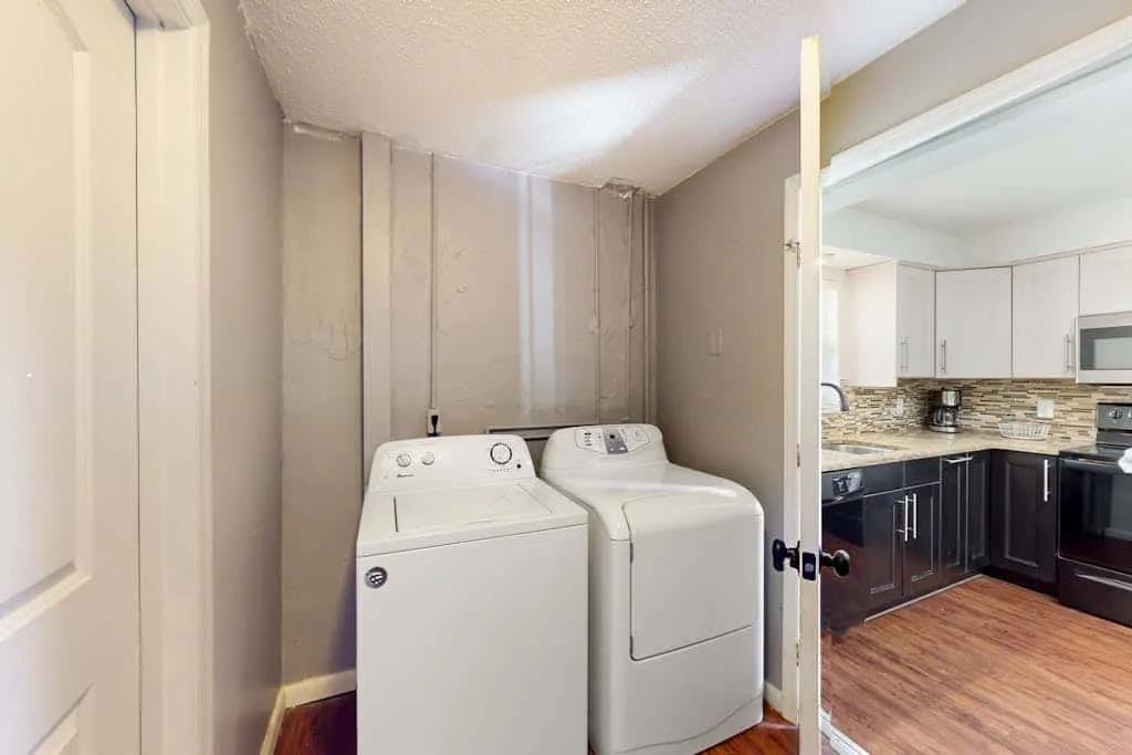 A laundry area with a washer and dryer beside an adjoining kitchen.