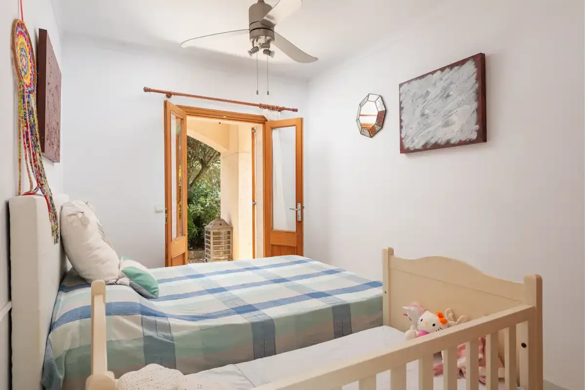 A bedroom with a blue-and-white checked bed and a wooden crib.