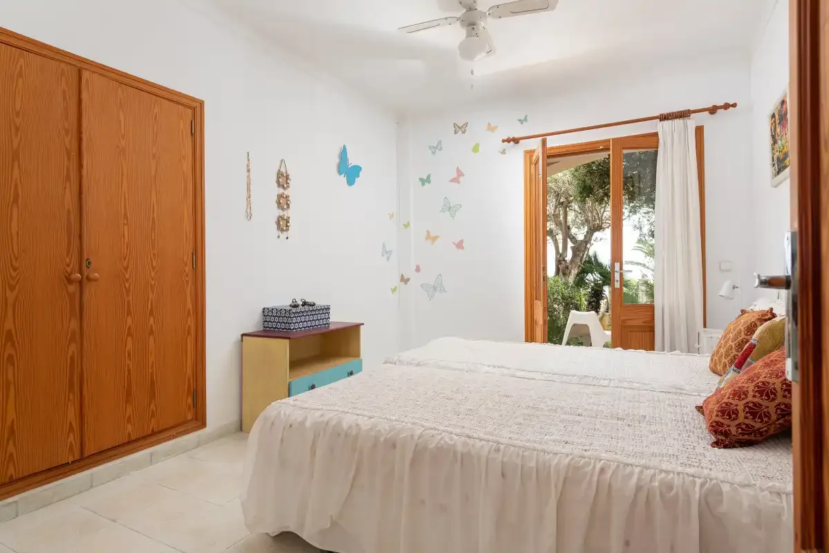 A bedroom with a bed and a glass door opening to greenery.