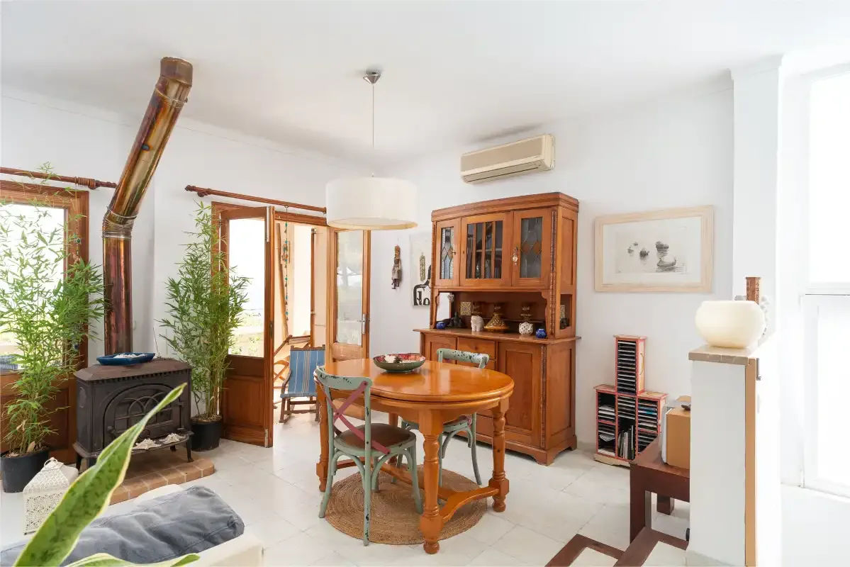 A bright living room with wooden seating, a fireplace, and a glass-front cabinet.
