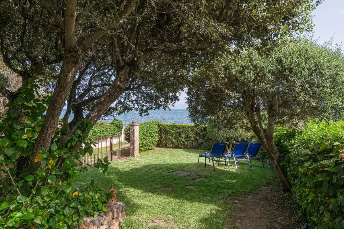 A garden with lawn seating and a view of the sea through the trees.