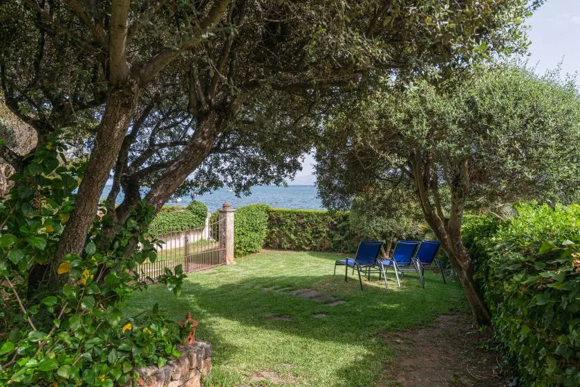 A shaded garden with outdoor seating and a view of the sea.