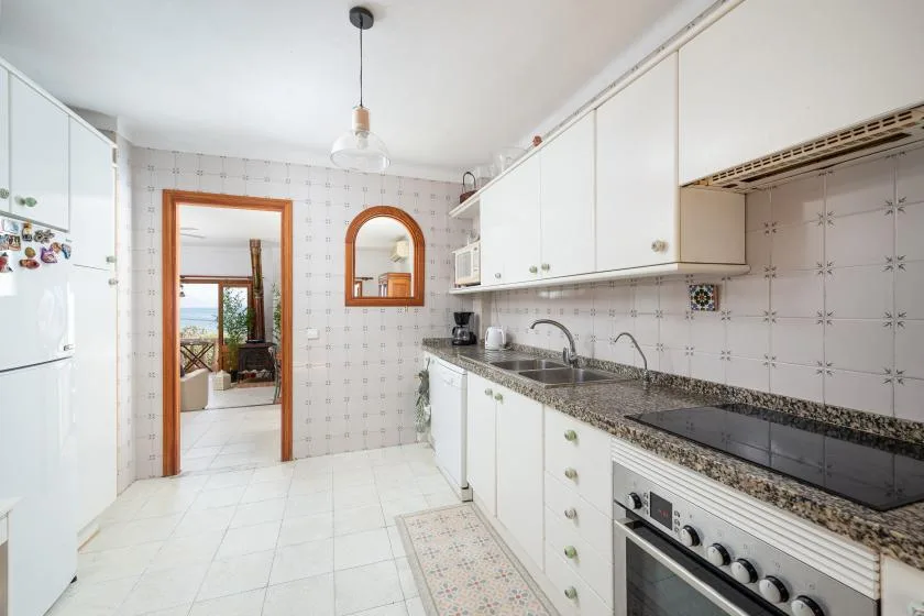 A bright kitchen with white cabinets, a countertop, and a stove.