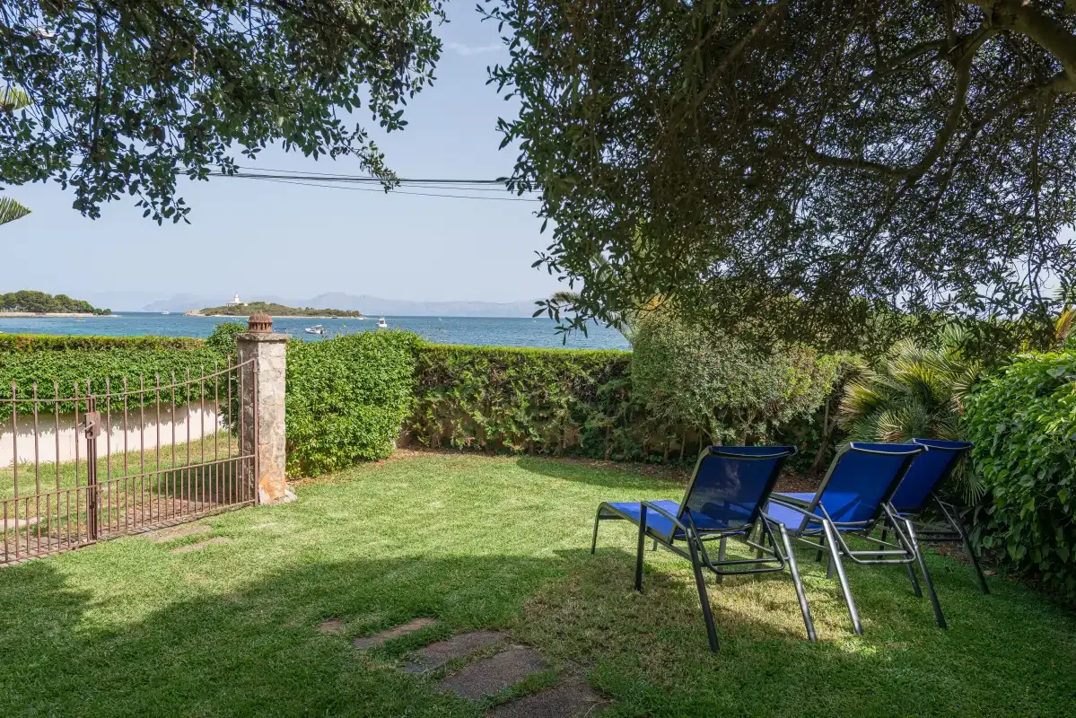 A grassy garden with lounge seating overlooks the sea.