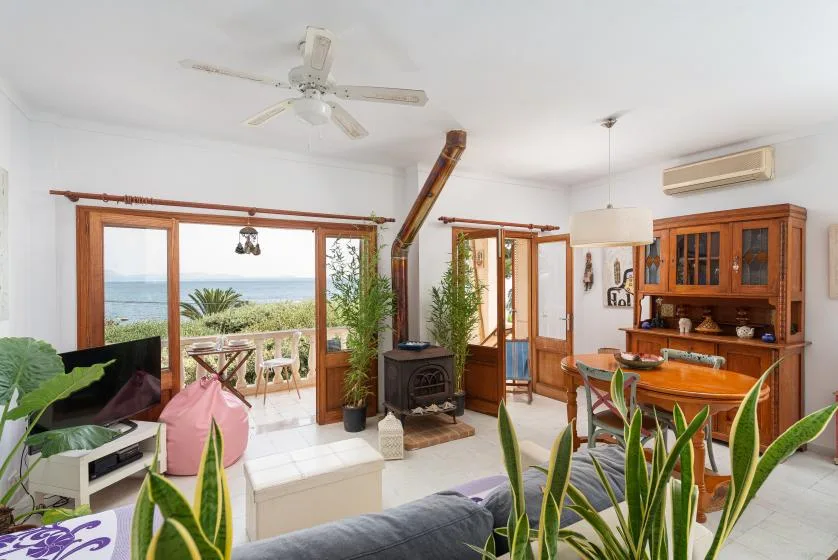 A bright living room opens onto a balcony with a view of the sea.