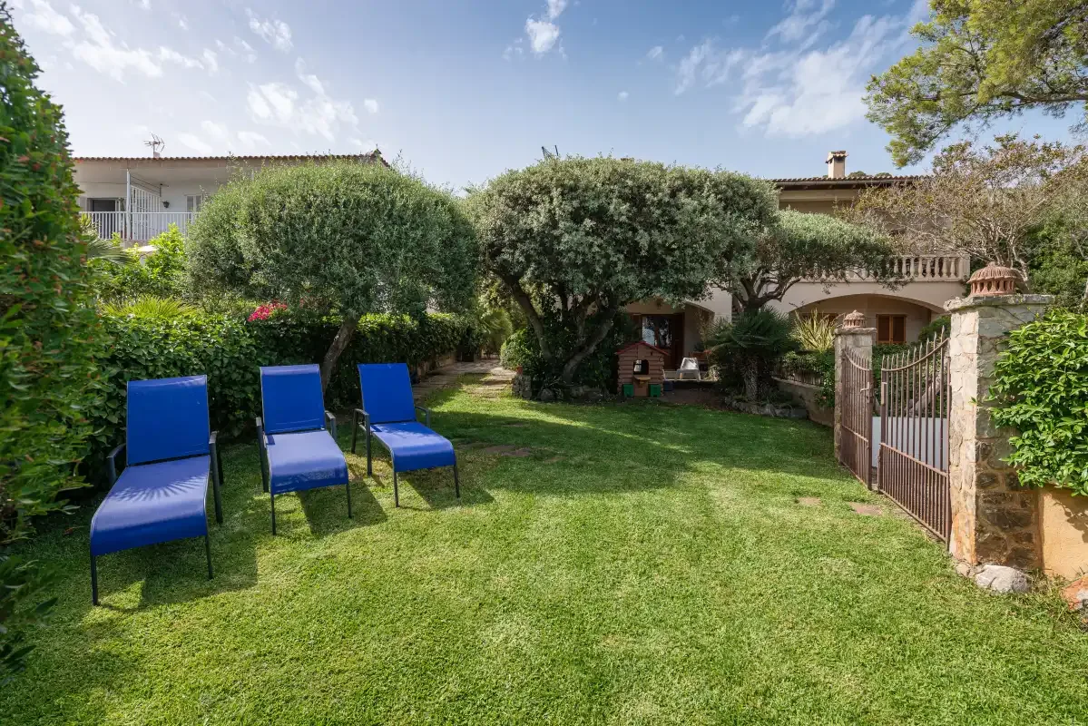 A garden lawn with blue seating and a gated entrance.