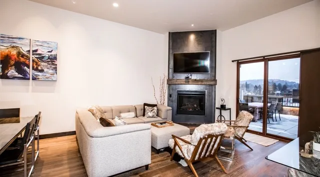 A living room with seating, a fireplace, and large glass doors opening to a balcony.