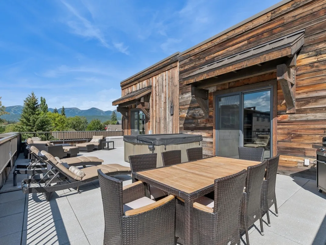 A wooden terrace with outdoor seating and mountain views.