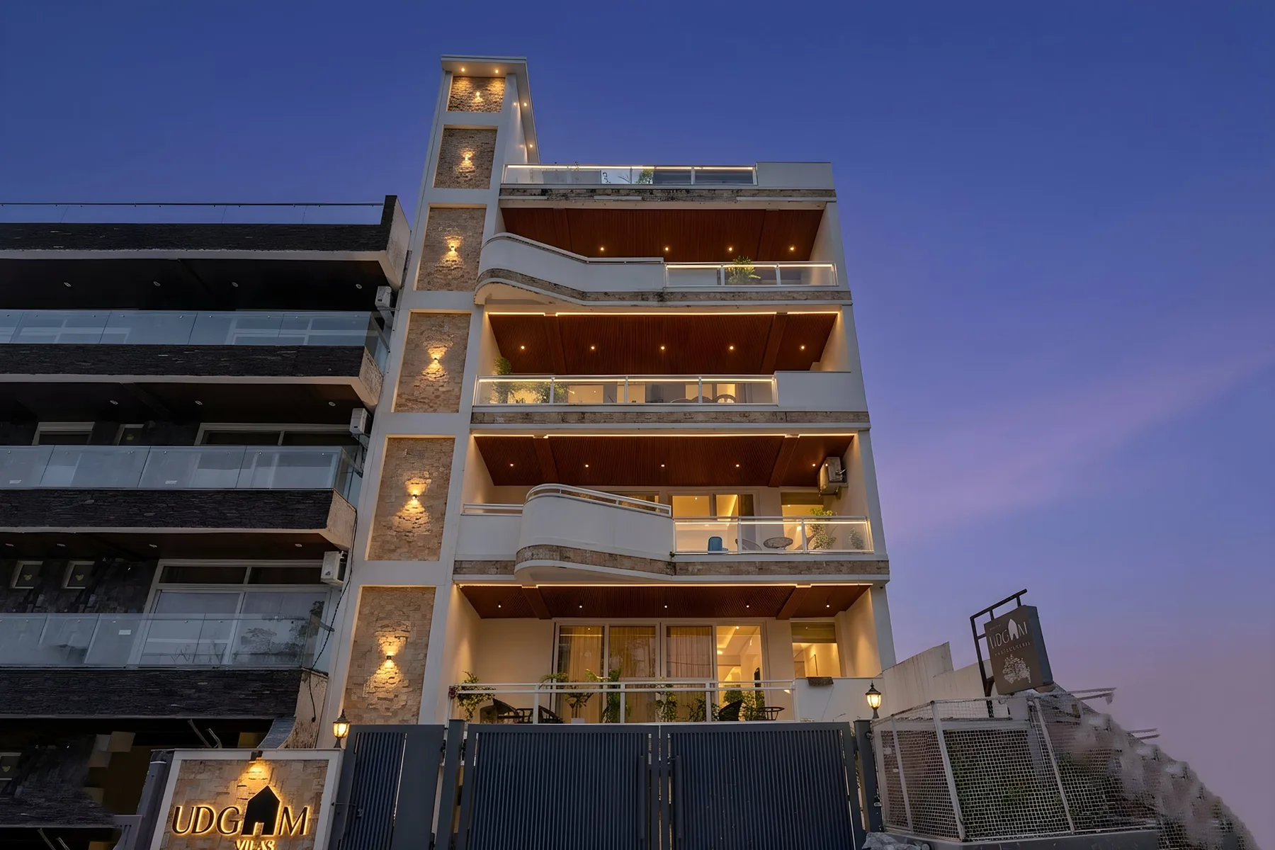 Un edificio moderno de varias plantas con balcones aparece al anochecer.