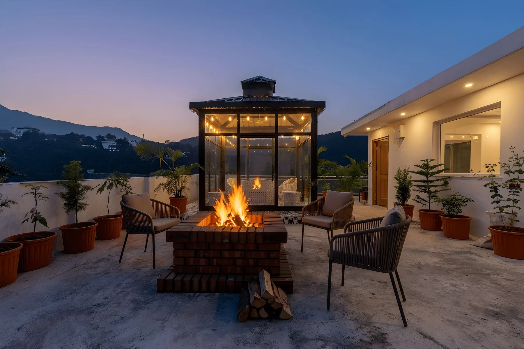 Una terraza en la azotea cuenta con una fogata encendida y asientos con vistas a las montañas.