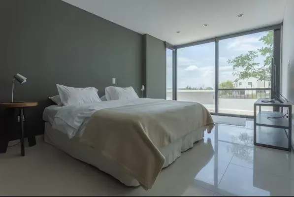 Un dormitorio con una cama grande junto a ventanales que dan a un balcón.